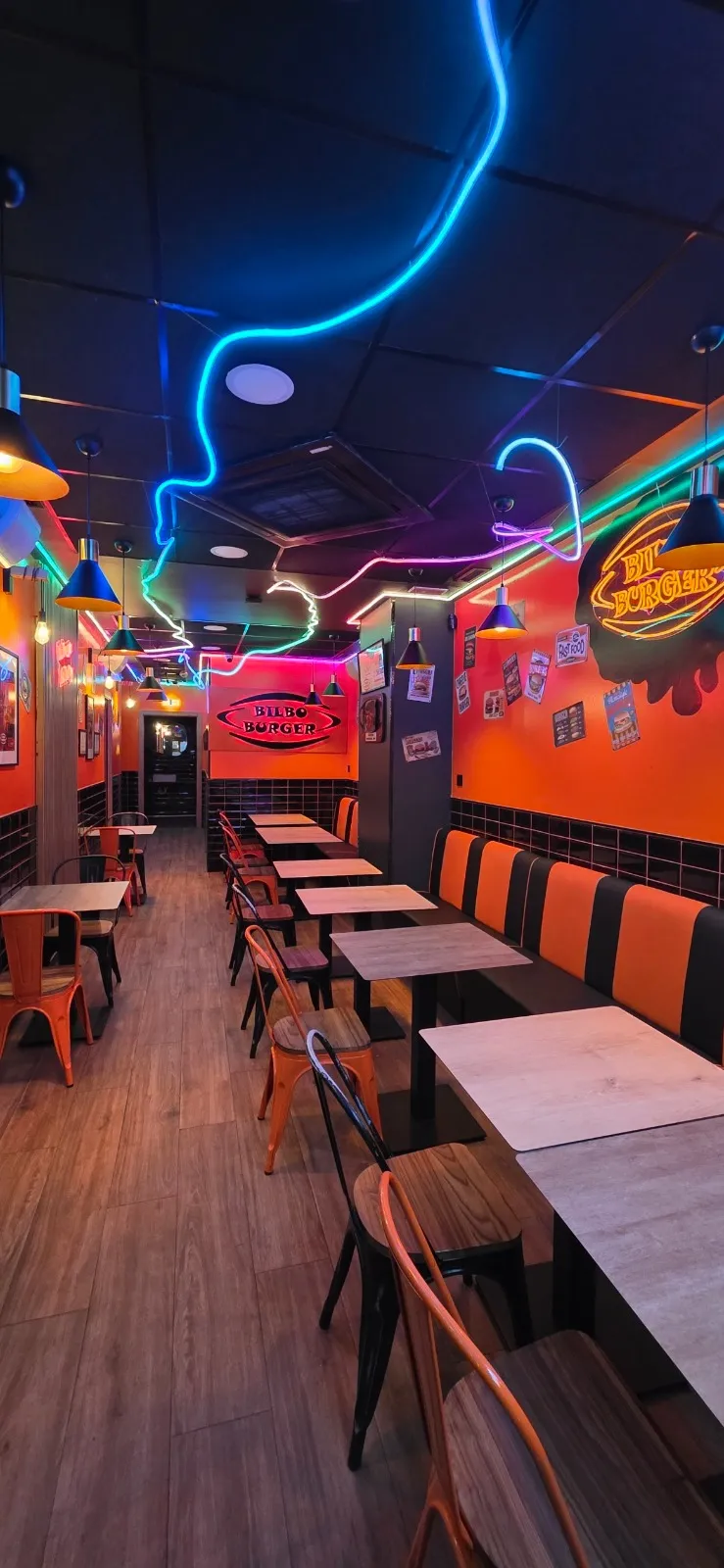 Interior del local de Bilbo Burger con neones y paredes naranjas